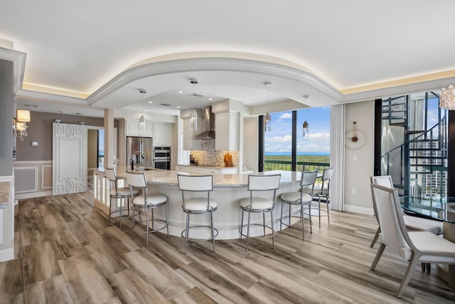 9900 S Ocean Dr Unit 1601, Jensen Beach, FL 34957 - kitchen featuring a tray ceiling, a kitchen bar, wall chimney range hood, and stainless steel appliances