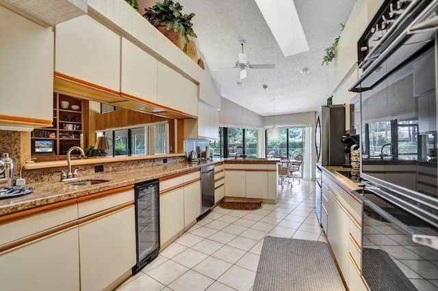 13179 Camero Way, Palm Beach Gardens, FL 33418 - kitchen with a sink, a skylight, a ceiling fan, a peninsula, and cream cabinets