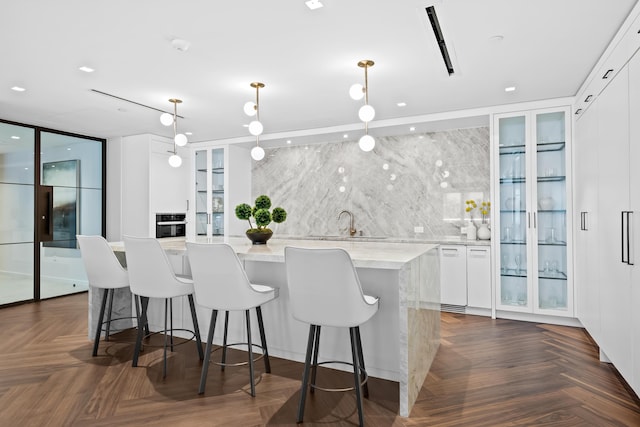 210 SE Mizner Blvd Unit 301, Boca Raton, FL 33432 - kitchen with white cabinetry, a center island, hanging light fixtures, glass insert cabinets, and a breakfast bar