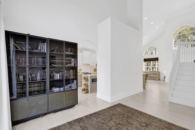 bar featuring stairway, light tile patterned flooring, a healthy amount of sunlight, and high vaulted ceiling