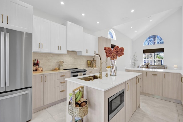 kitchen featuring a sink, stainless steel appliances, light tile patterned floors, tasteful backsplash, and an island with sink