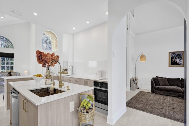 kitchen featuring arched walkways, modern cabinets, stainless steel oven, and open floor plan