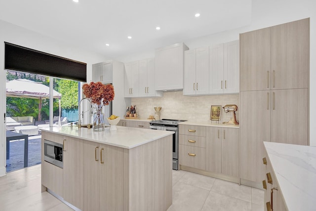kitchen with light stone counters, stainless steel appliances, recessed lighting, a center island with sink, and backsplash