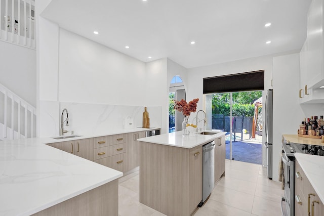 kitchen featuring appliances with stainless steel finishes, modern cabinets, light stone countertops, and a sink