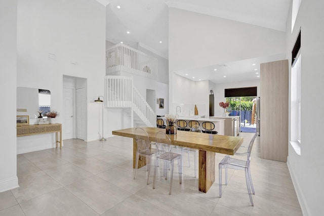 dining area featuring stairs, high vaulted ceiling, and baseboards