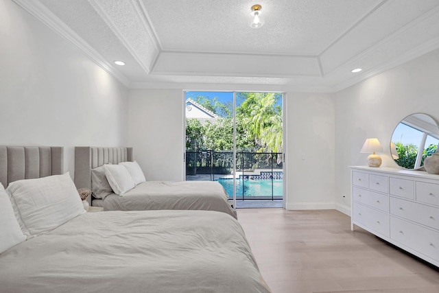 bedroom featuring light wood finished floors, multiple windows, access to outside, and a raised ceiling