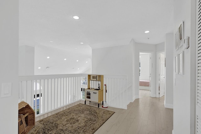 hall featuring baseboards, recessed lighting, light wood-type flooring, and an upstairs landing
