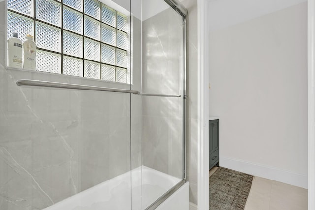 bathroom featuring bath / shower combo with glass door and baseboards