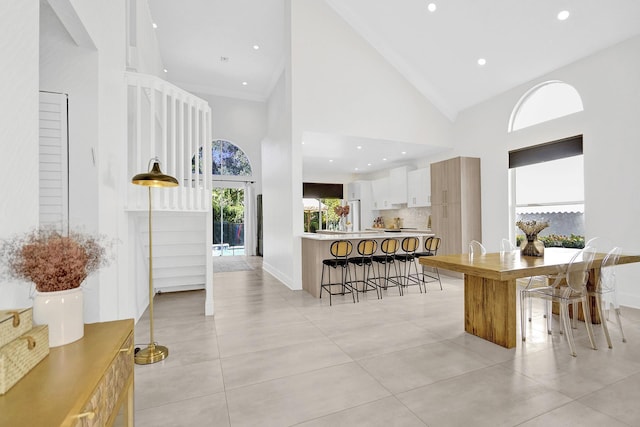 interior space featuring a breakfast bar, light countertops, white cabinetry, high vaulted ceiling, and a peninsula