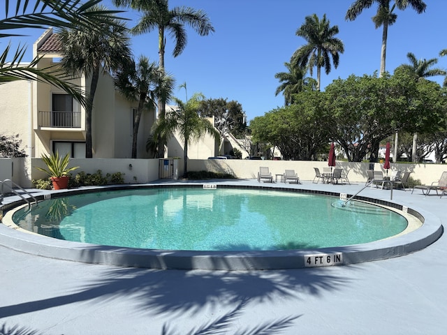 community pool with a patio and fence