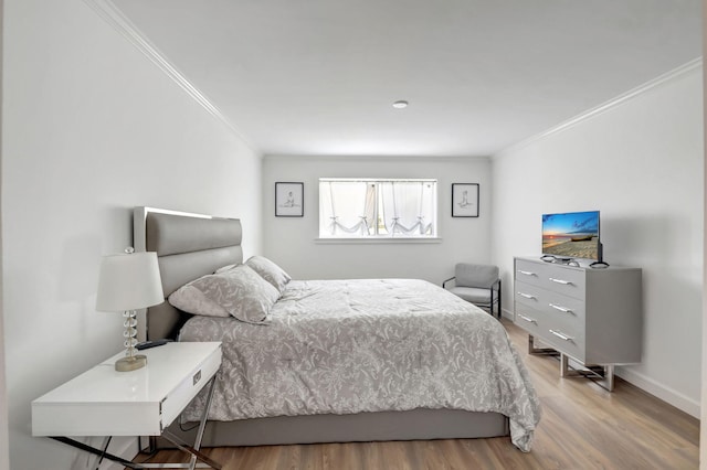 bedroom with wood finished floors, baseboards, and ornamental molding