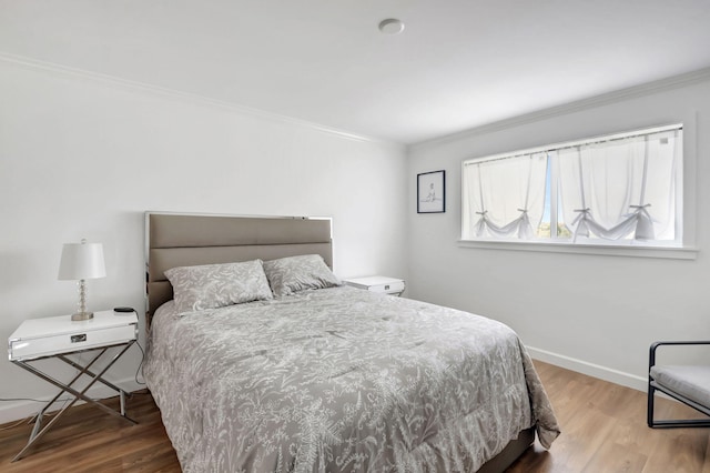 bedroom featuring ornamental molding, baseboards, and wood finished floors