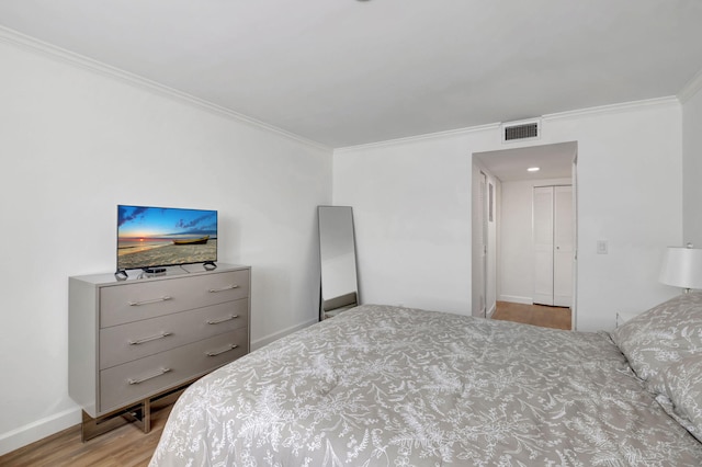 bedroom featuring visible vents, baseboards, ornamental molding, and wood finished floors