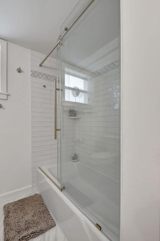 bathroom with baseboards and shower / bath combination with glass door