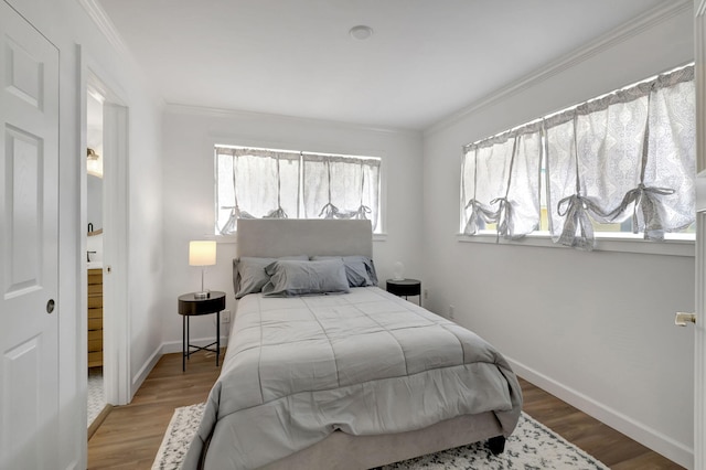 bedroom with crown molding, wood finished floors, and baseboards