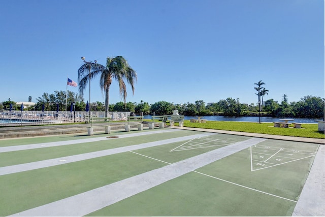 view of home's community featuring a yard, fence, a water view, and shuffleboard