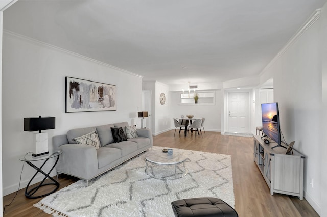 living area with wood finished floors, baseboards, and ornamental molding