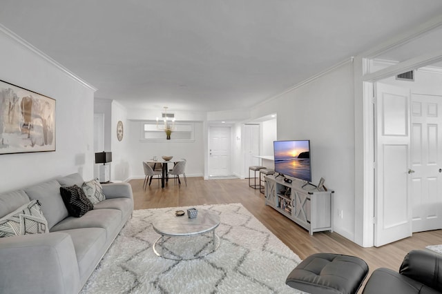living room featuring wood finished floors, baseboards, ornamental molding, and visible vents