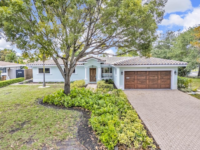 view of front facade featuring fence, driveway, a tile roof, a garage, and a front yard