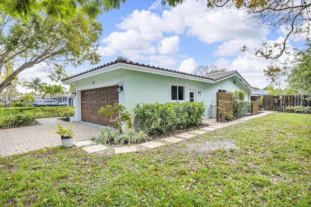 view of home's exterior featuring driveway, a tiled roof, fence, a garage, and stucco siding