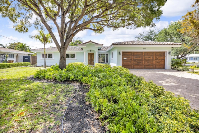 view of front facade with a tile roof, an attached garage, stucco siding, and driveway