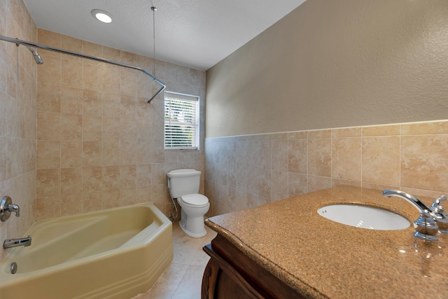 full bathroom with toilet, bathtub / shower combination, tile walls, a textured wall, and vanity