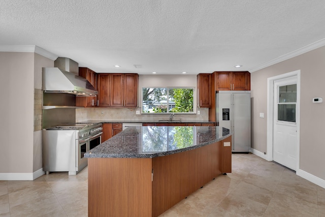 kitchen featuring dark stone countertops, high quality appliances, wall chimney range hood, a kitchen island, and tasteful backsplash
