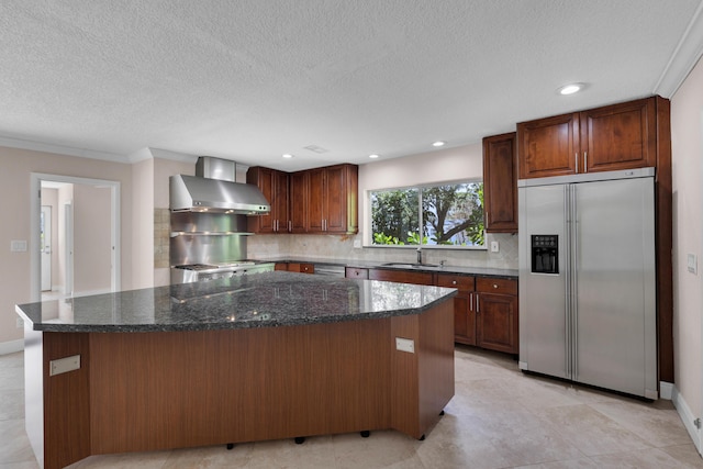 kitchen with a sink, a kitchen island, wall chimney range hood, stainless steel appliances, and tasteful backsplash