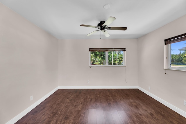 spare room with dark wood finished floors, baseboards, and ceiling fan