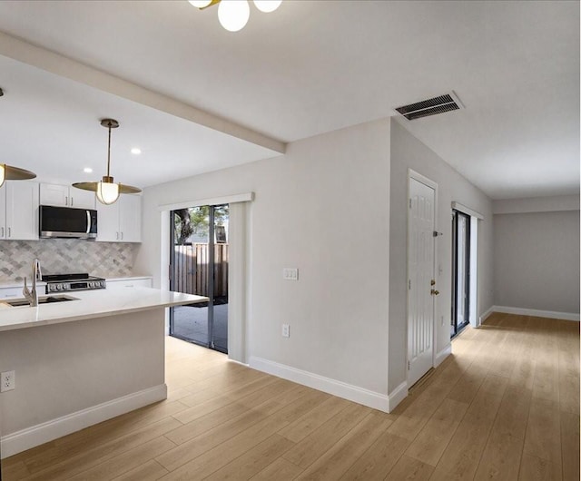 6201 62nd Way, West Palm Beach, FL 33409 - kitchen with stainless steel appliances, a sink, white cabinetry, light wood-style flooring, and decorative backsplash