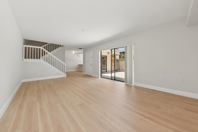 6201 62nd Way, West Palm Beach, FL 33409 - unfurnished living room with light wood-style flooring, baseboards, and stairs