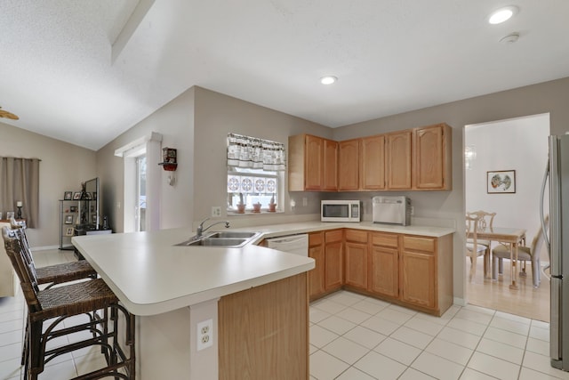 kitchen featuring a kitchen breakfast bar, light countertops, white appliances, a sink, and a peninsula