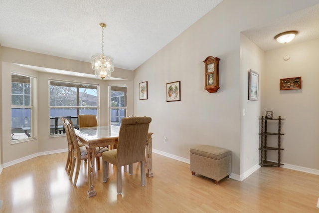 dining space with a chandelier, light wood-style flooring, lofted ceiling, and baseboards