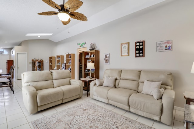 living area featuring a ceiling fan, lofted ceiling with skylight, and light tile patterned floors