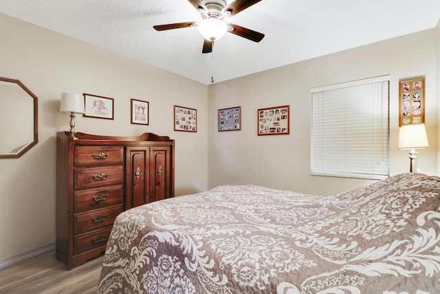 bedroom featuring light wood-style flooring, a ceiling fan, and baseboards