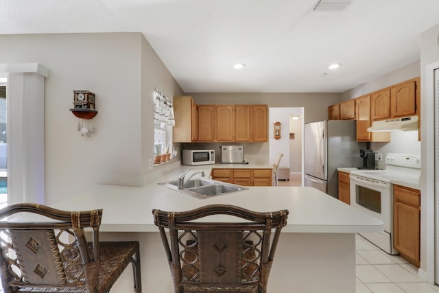 kitchen featuring a peninsula, a sink, white appliances, light countertops, and under cabinet range hood