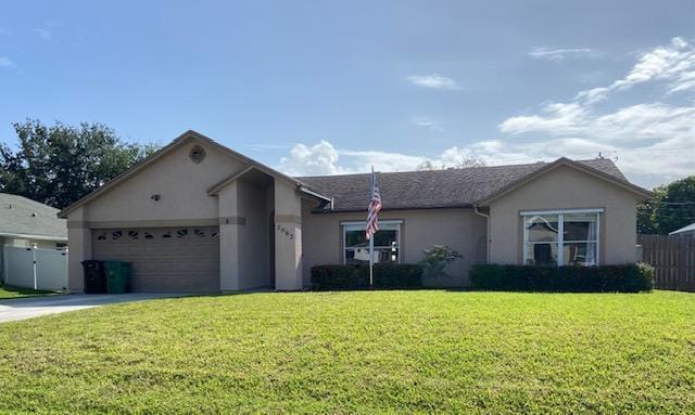 single story home featuring an attached garage, fence, concrete driveway, a front lawn, and stucco siding