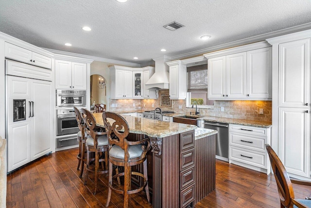 21281 Waycross Dr, Boca Raton, FL 33428 - kitchen featuring stainless steel appliances, a sink, custom exhaust hood, arched walkways, and a warming drawer