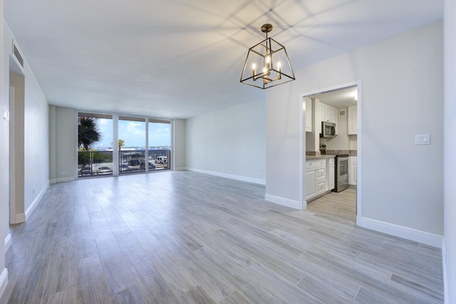 2800 N Flagler Dr Unit 207, West Palm Beach, FL 33407 - unfurnished room featuring light wood-type flooring, visible vents, a wall of windows, a chandelier, and baseboards