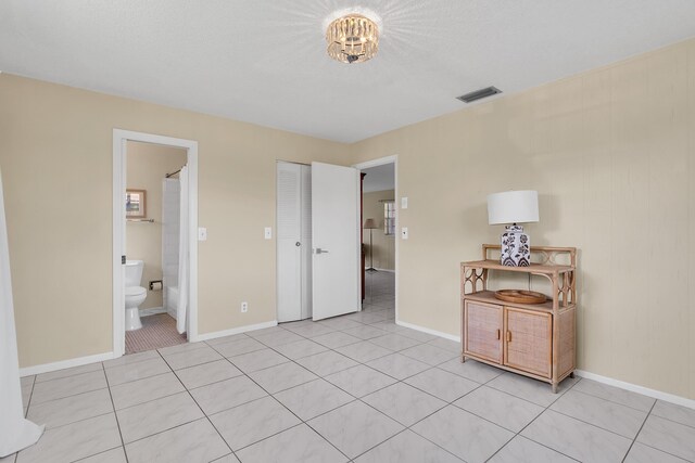 155 Mockingbird Ln, Delray Beach, FL 33445 - unfurnished bedroom with light tile patterned floors, visible vents, baseboards, and ensuite bath