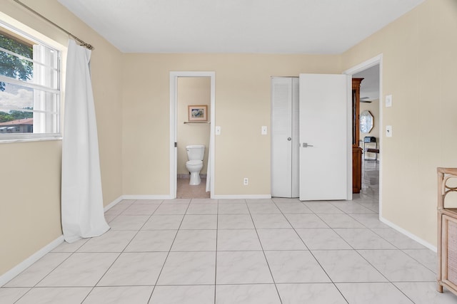 155 Mockingbird Ln, Delray Beach, FL 33445 - unfurnished bedroom featuring light tile patterned floors, baseboards, and ensuite bath