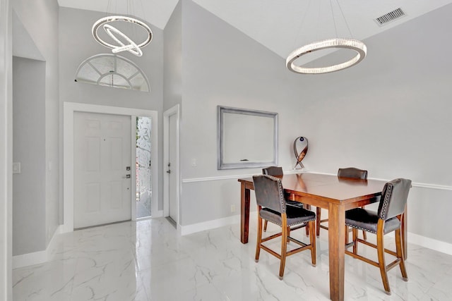 dining space featuring visible vents, baseboards, a notable chandelier, a high ceiling, and marble finish floor