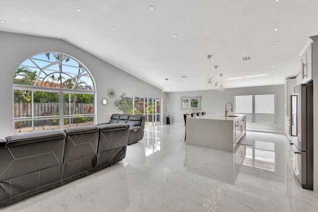 living area featuring visible vents, marble finish floor, vaulted ceiling, and a textured ceiling