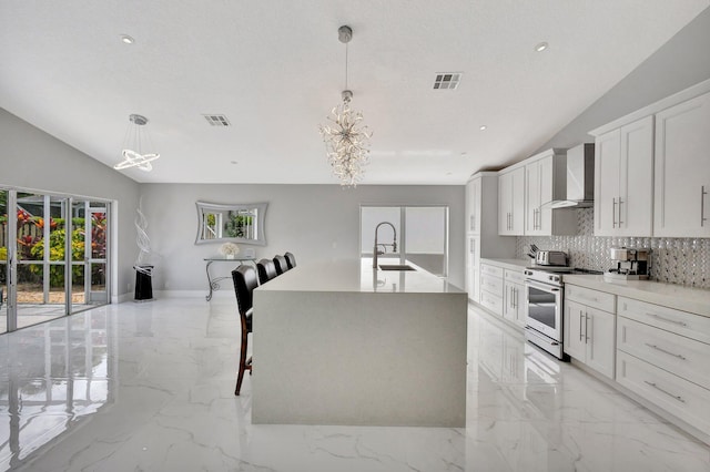 kitchen featuring marble finish floor, an inviting chandelier, stainless steel electric stove, and wall chimney exhaust hood