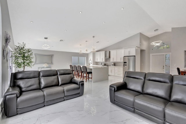 living area with marble finish floor, high vaulted ceiling, an inviting chandelier, and visible vents