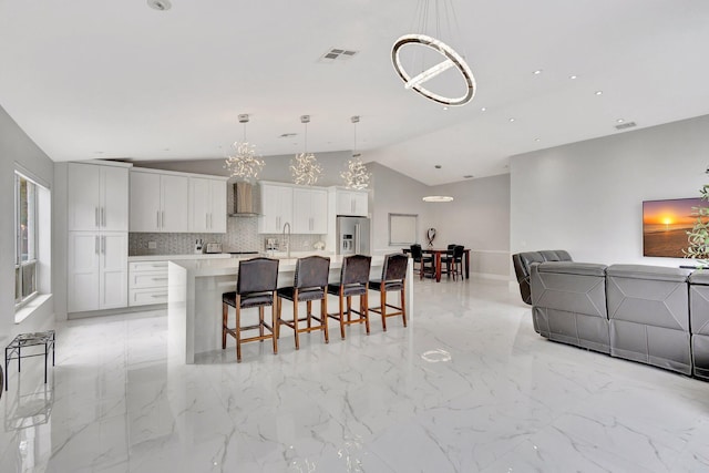 kitchen featuring visible vents, stainless steel refrigerator with ice dispenser, a notable chandelier, open floor plan, and a kitchen breakfast bar