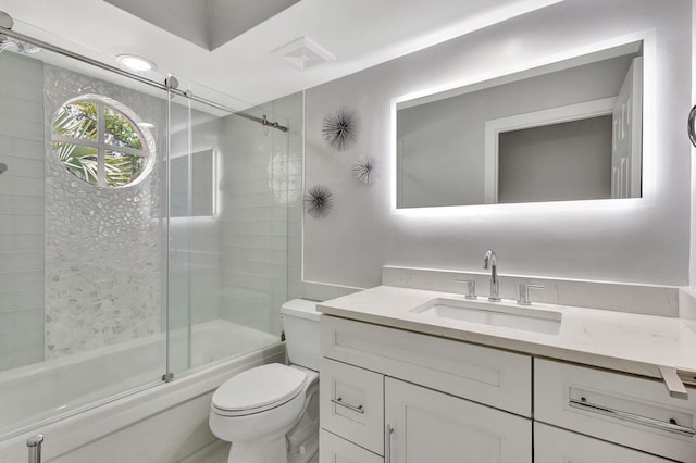 full bathroom featuring toilet, vanity, combined bath / shower with glass door, and visible vents