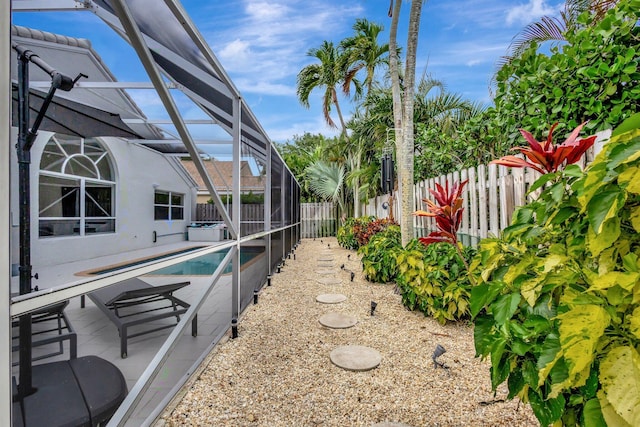 view of yard with a fenced in pool, a patio, a fenced backyard, and glass enclosure