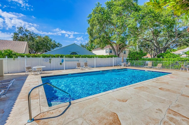 community pool with a patio and fence