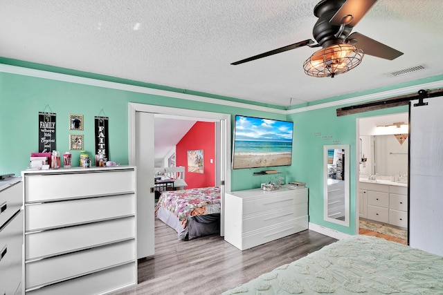 3750 NW 73rd Way, Coral Springs, FL 33065 - bedroom featuring a barn door, wood finished floors, a textured ceiling, a ceiling fan, and connected bathroom